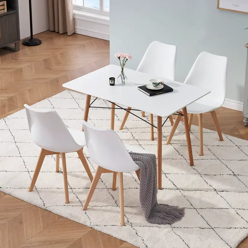 Lot de 4 chaises scandinaves blanches dans une salle à manger lumineuse