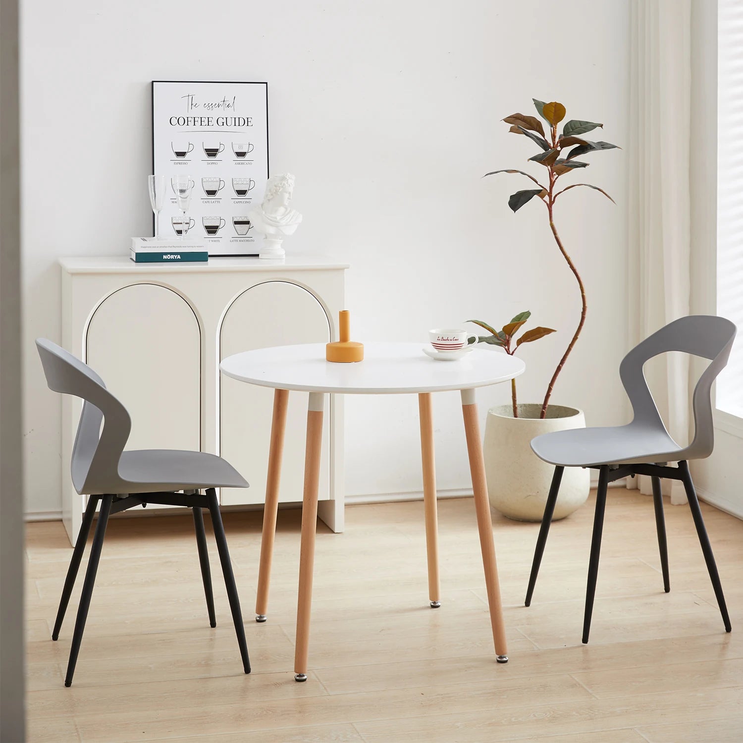 Chaises contemporaines grises autour d’une table blanche avec pieds en bois, ambiance minimaliste et moderne.