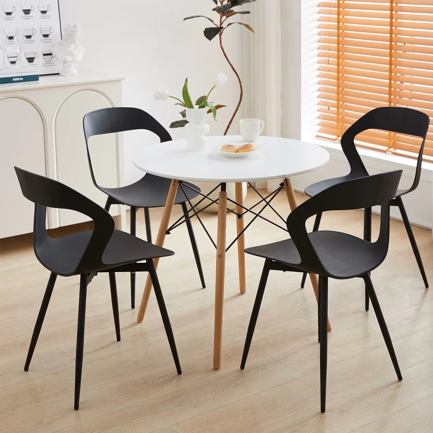 Lot de 6 chaises contemporaines noires disposées autour d’une table ronde en bois dans une salle à manger moderne.
