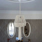 Lustre en macramé suspendu installé dans une pièce avec des miroirs muraux.