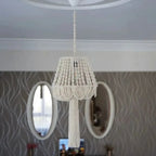 Lustre en macramé suspendu installé dans une pièce avec des miroirs muraux.