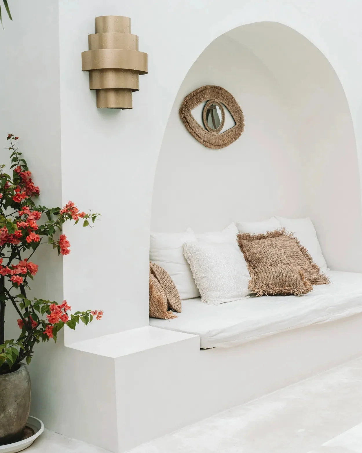 Banquette blanche avec coussins sous un alcôve en forme d’œil, idéal pour décoration intérieure