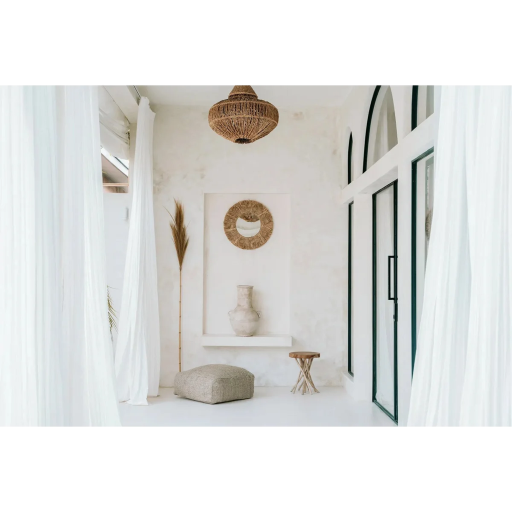 Miroir mural rond en raphia naturel et coquillages dans une pièce blanche minimaliste boho