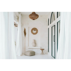 Miroir mural rond en raphia naturel et coquillages dans une pièce blanche minimaliste boho