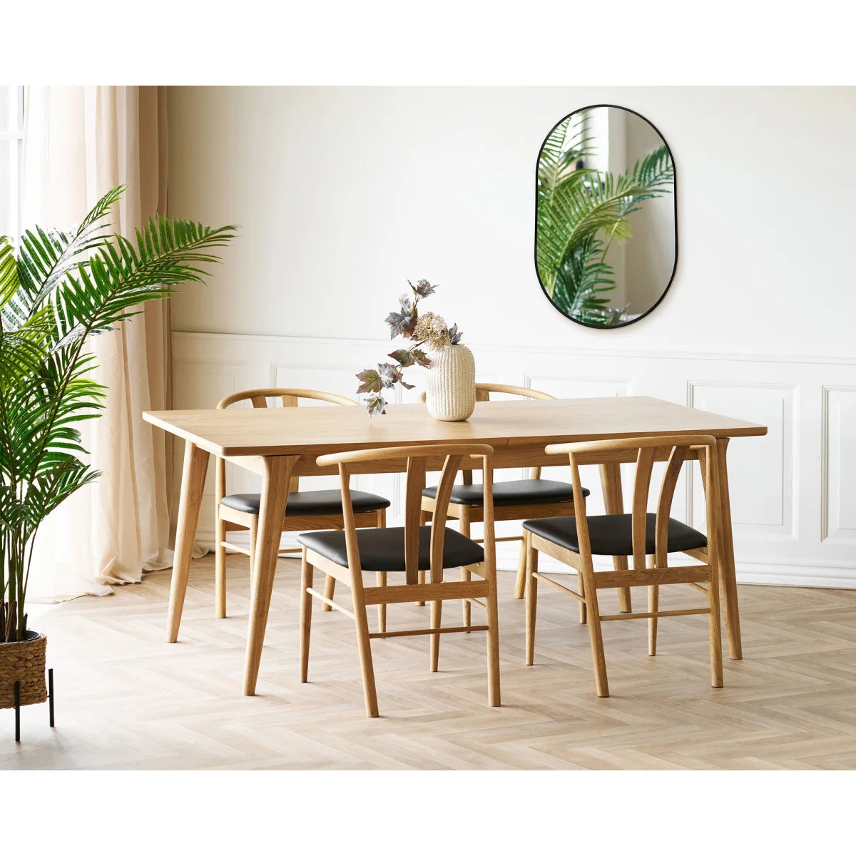 Table à manger en bois clair avec 4 chaises rembourrées noires et cadres courbes