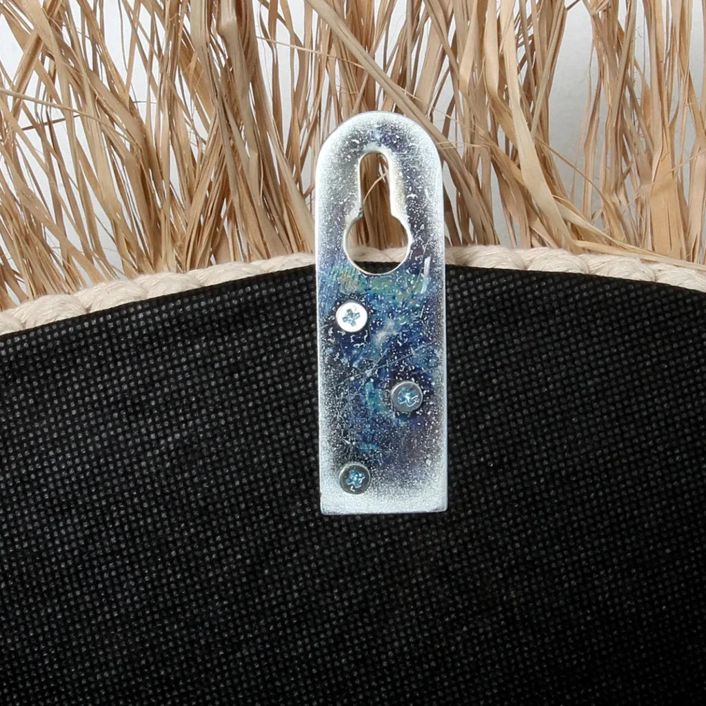 Support en métal fixé à une surface noire texturée avec de la paille au-dessus pour le Miroir rond 75 cm en Raphia et Coquillages Naturel Blanc