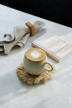 Tasse en céramique crème avec latte art mousseux sur sous-verre tissé