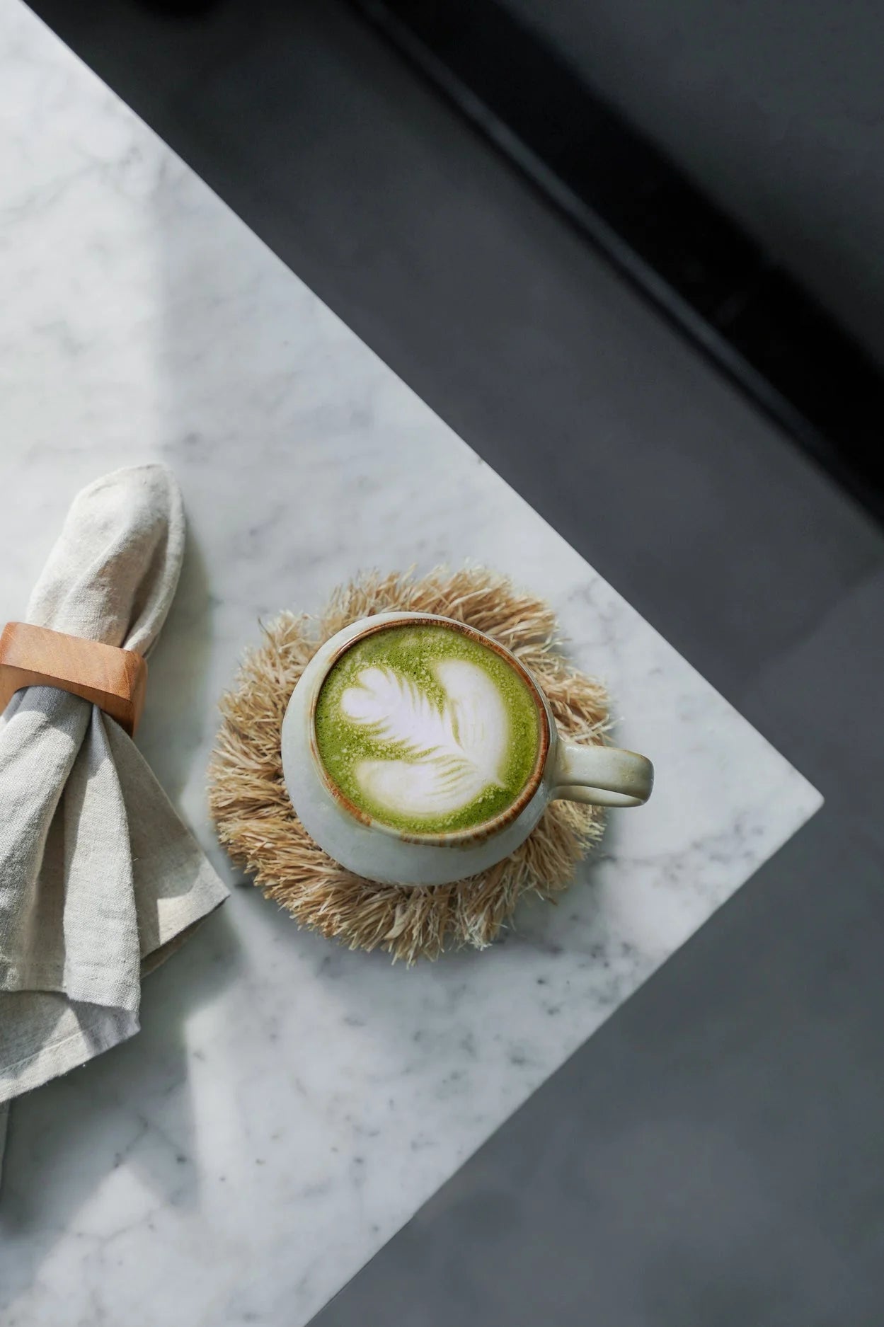 Mug en céramique crème avec latte matcha vert clair et mousse blanche sur sous-verre