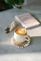 Tasse en grès blanc mat effet nuagé avec latte art sur sous-verre coquillages