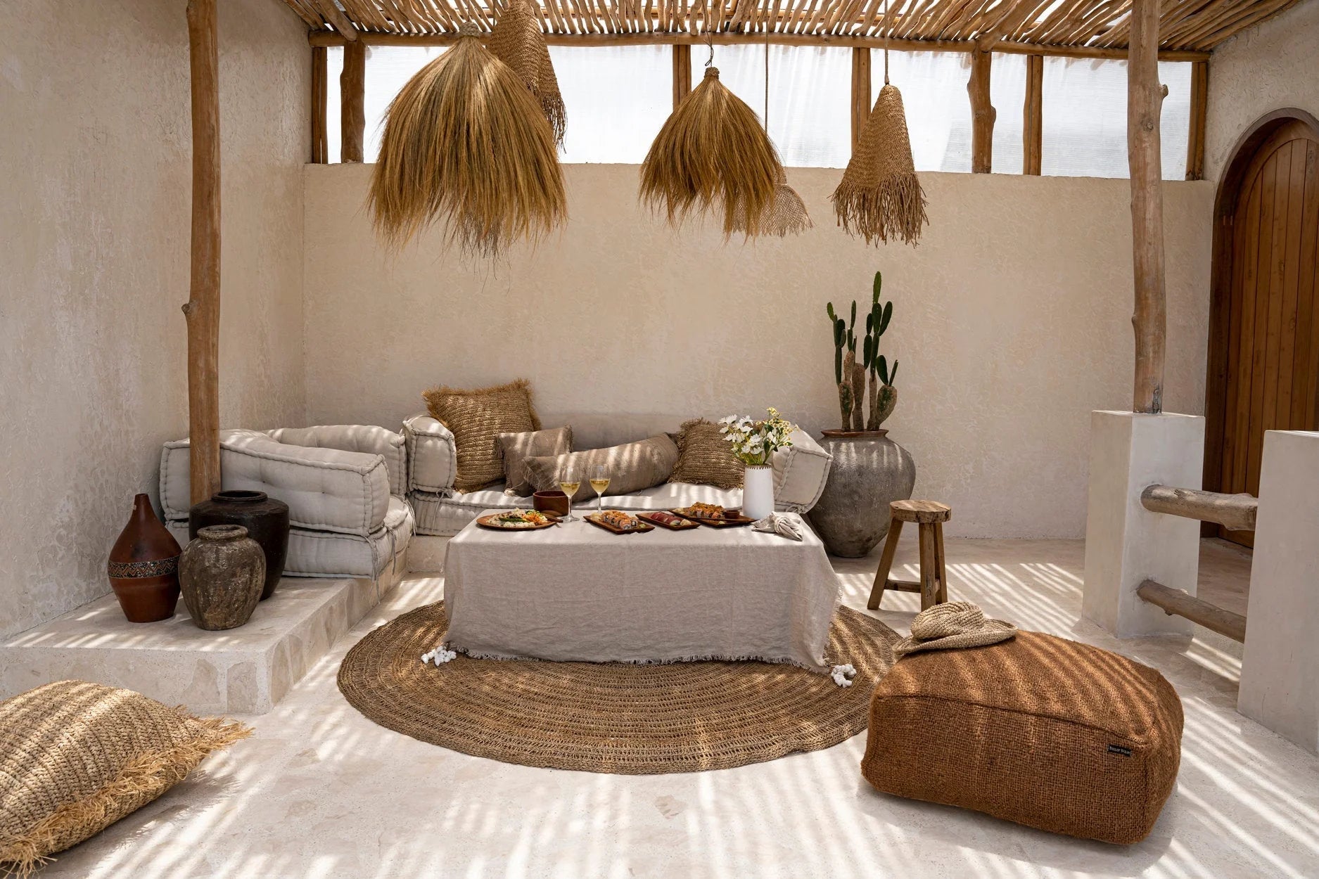 Coin lounge extérieur avec décoration bohème naturelle et nappe carrée en lin beige