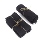Deux bundles de tissu noir en lin, un plié et un roulé, liés avec de la ficelle