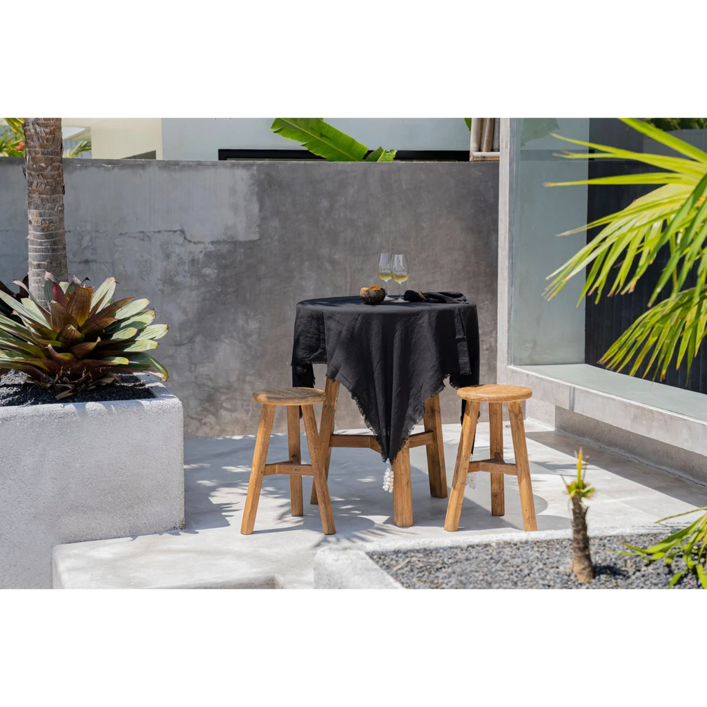 Nappe en lin noir 150x200 cm sur une table ronde extérieure avec deux tabourets en bois