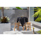 Nappe en lin noir 150x200 cm sur une table ronde extérieure avec deux tabourets en bois