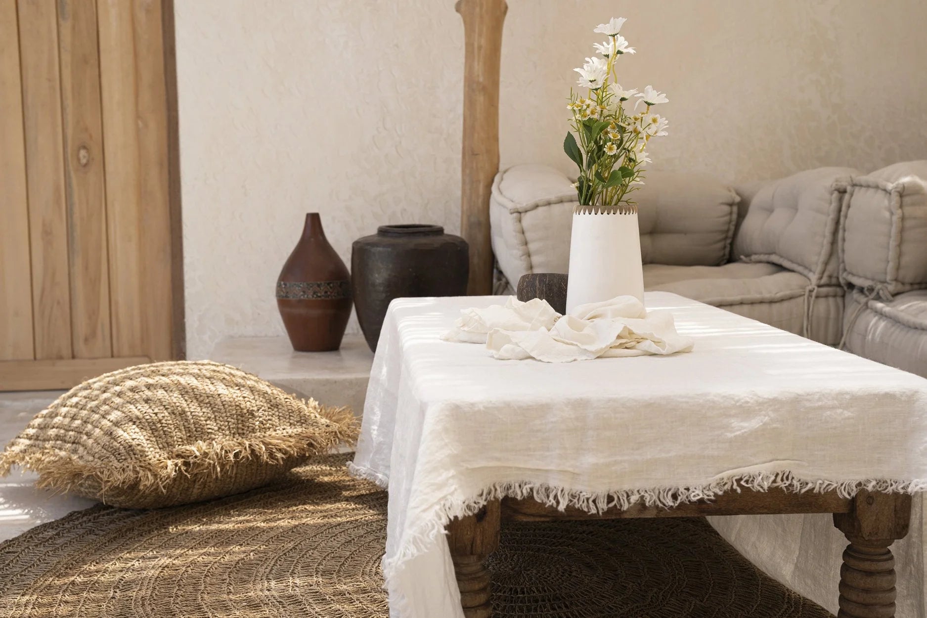 Nappe rectangulaire en lin blanc cassé avec bordures frangées sur une table rustique