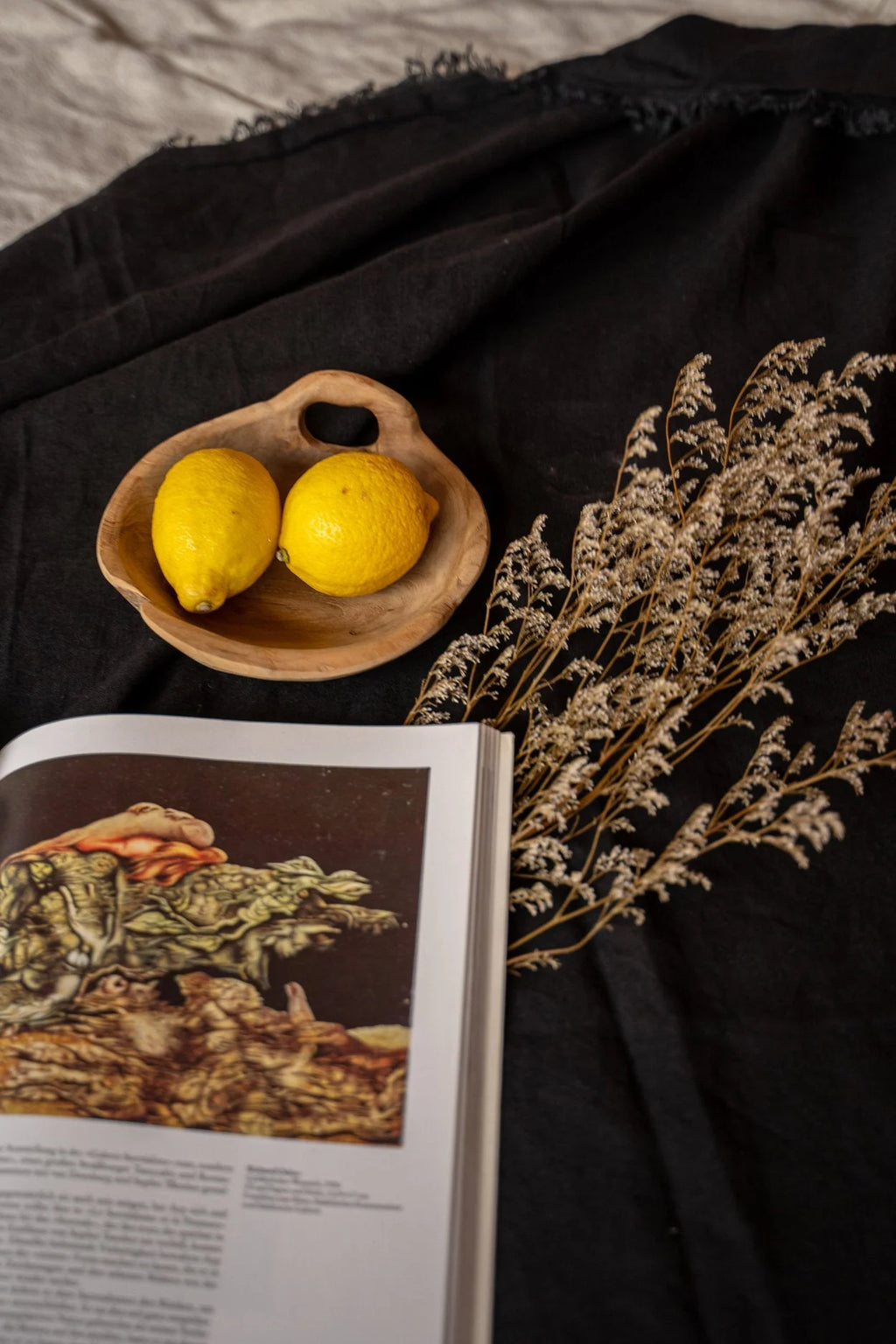 Deux citrons jaunes dans bol en bois rustique sur nappe lin noir frangé