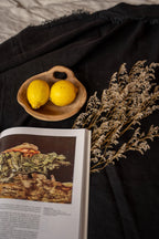 Deux citrons jaunes dans bol en bois rustique sur nappe lin noir frangé