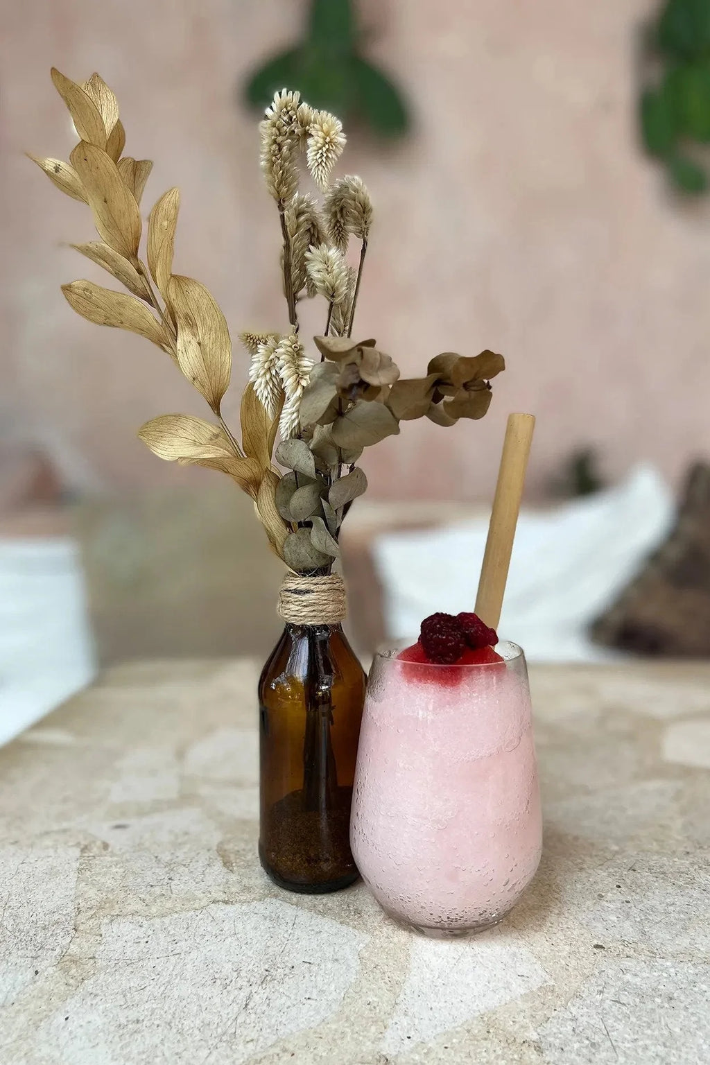 Smoothie rose dans une paille en bambou naturel avec arrangement floral