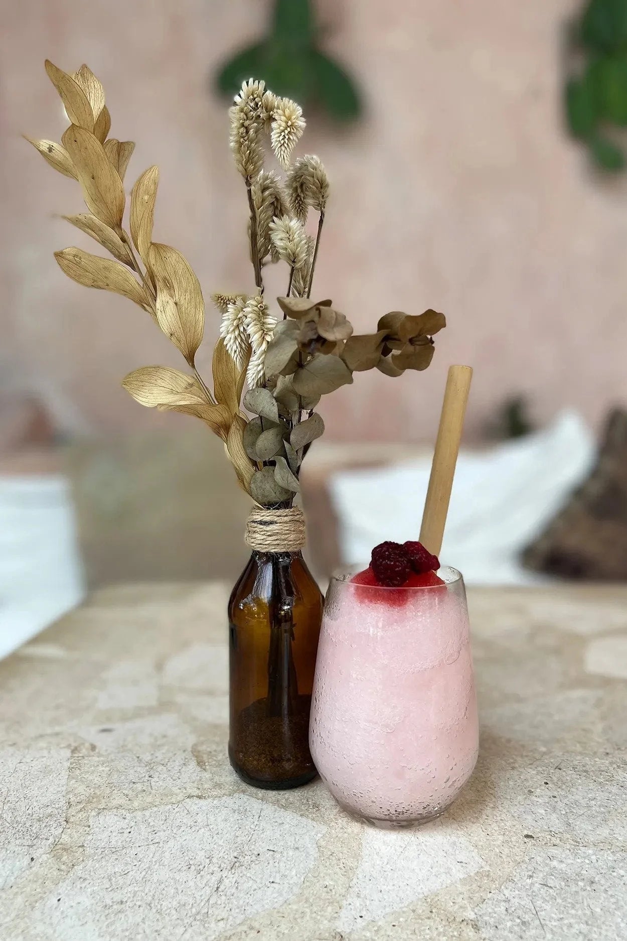 Smoothie rose dans une paille en bambou naturel avec arrangement floral