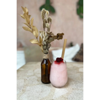 Boisson rose avec topping rouge et paille en bambou, bouteille avec feuilles séchées