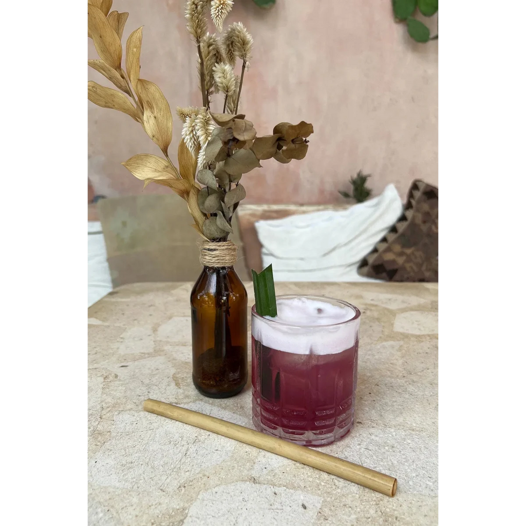 Verre avec boisson violette, mousse blanche et feuille de bambou pour pailles réutilisables