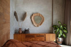 Commode en bois avec miroir tressé et vase triangle en feuilles de bananier