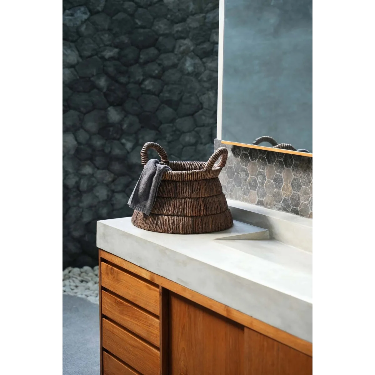 Panier en feuilles de bananier tressées triangle avec anse en osier et tissu gris sur comptoir béton