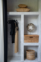 Closet intégré avec vêtements et paniers en fibres naturelles tressées beige ronde