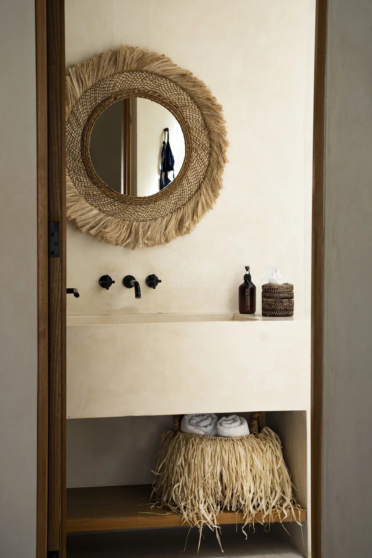 Lavabo de salle de bain style bohème avec accents en paille et panier rond en feuilles de bananier