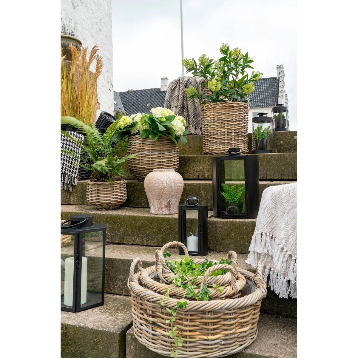 Panier rond en rotin tressé gris avec anses, lierre vert dedans