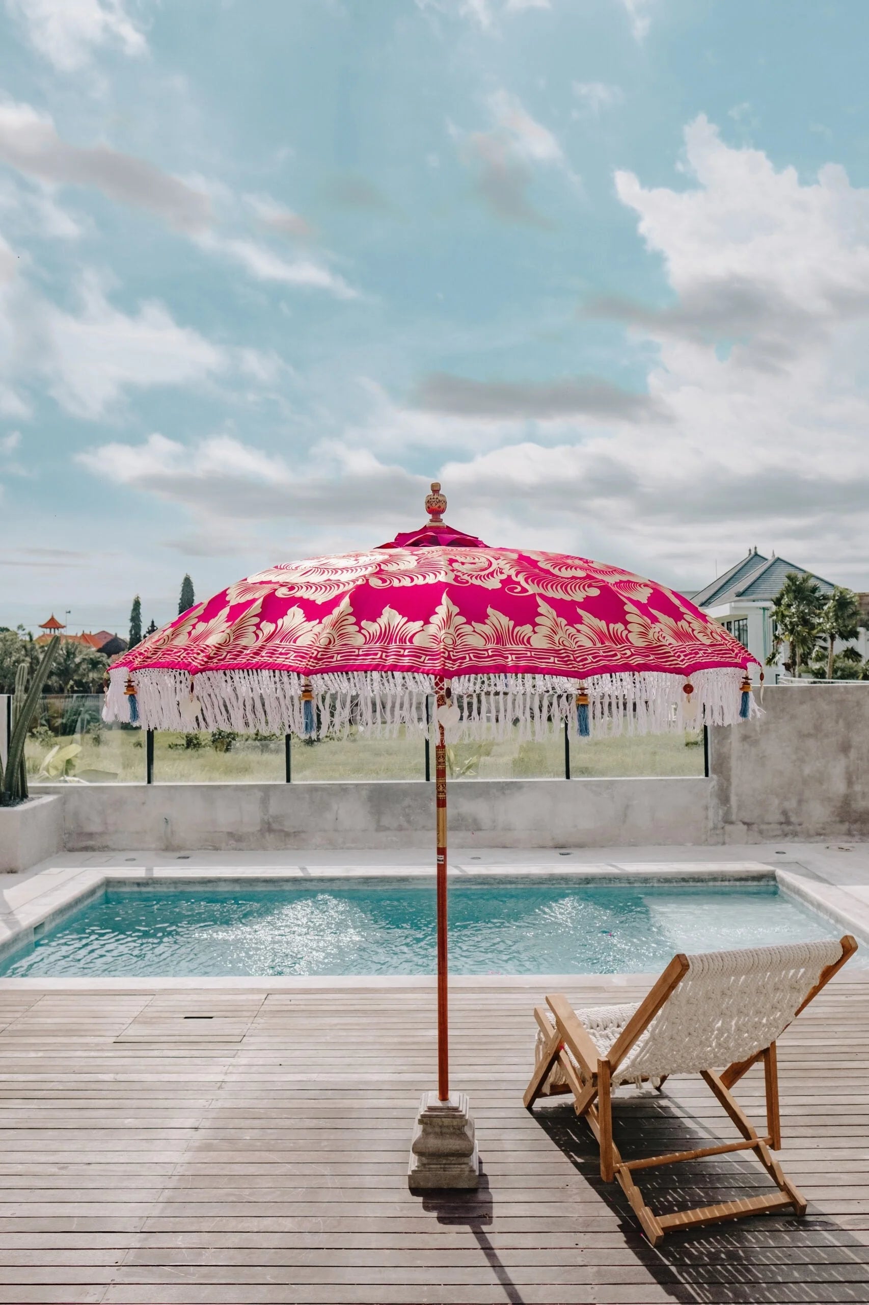 Parasol balinais rond en tissu fuchsia avec franges blanches et motifs dorés