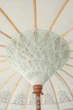 Parasol rond bleu pastel à franges avec motifs tropicaux et ombrage blanc