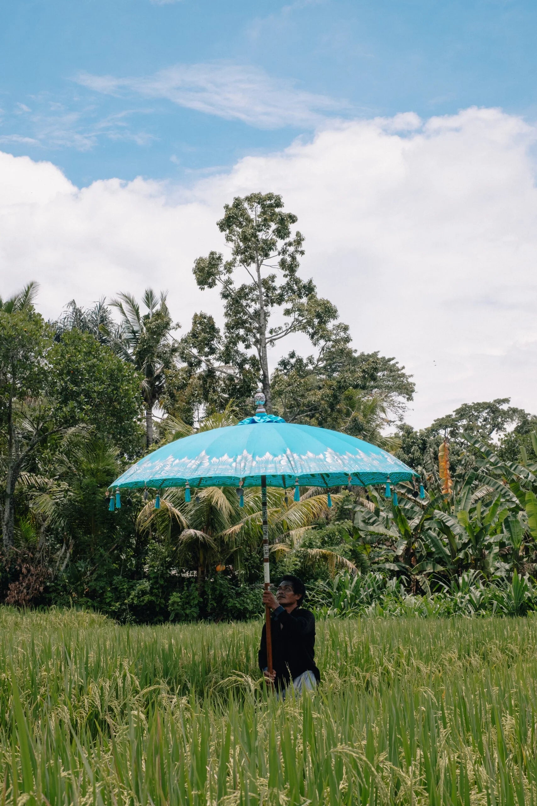 Deux parasols décoratifs turquoise avec motifs balinais et pompons suspendus