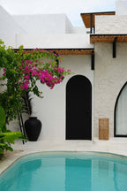 Pendentif Takuhanki Naturel devant une piscine turquoise avec murs blancs