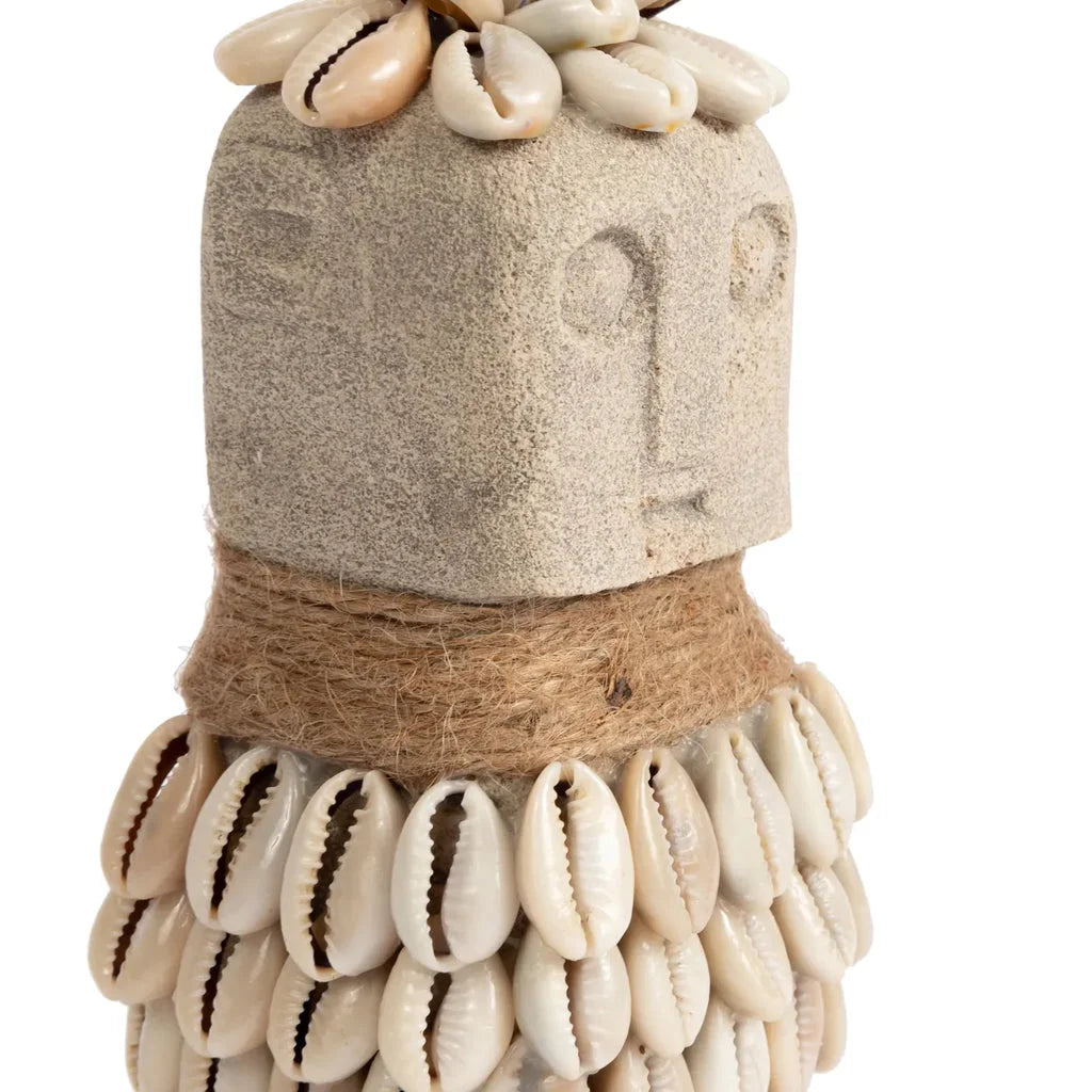 Figure en pierre ornée de coquillages et de ficelle.