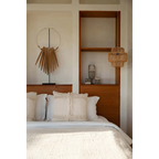 Lit avec tête de lit en bois, linge blanc et coussins décoratifs, Pierre de Sumba