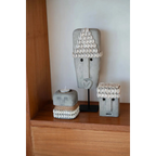 Objets décoratifs artisanaux en grès gris avec coquillages blancs, inspirés de visages abstraits