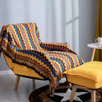 Couverture en plaid chevron coloré sur fauteuil jaune, parfaite pour des moments cocooning