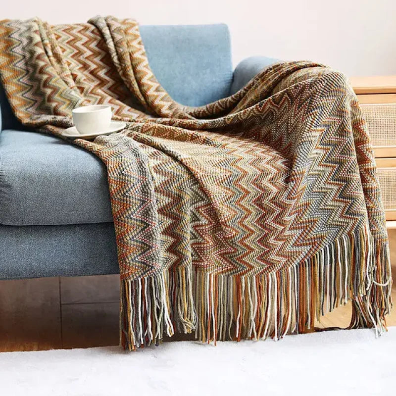 Couverture à motifs Plaid Chevron avec frange sur un canapé bleu pour moments cocooning