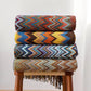 Piles de plaids chevron colorés sur un tabouret en bois pour des moments cocooning