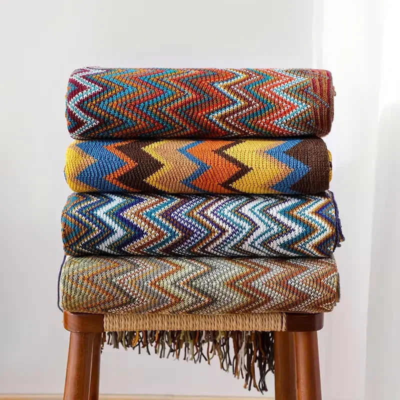 Piles de plaids chevron colorés sur un tabouret en bois pour des moments cocooning