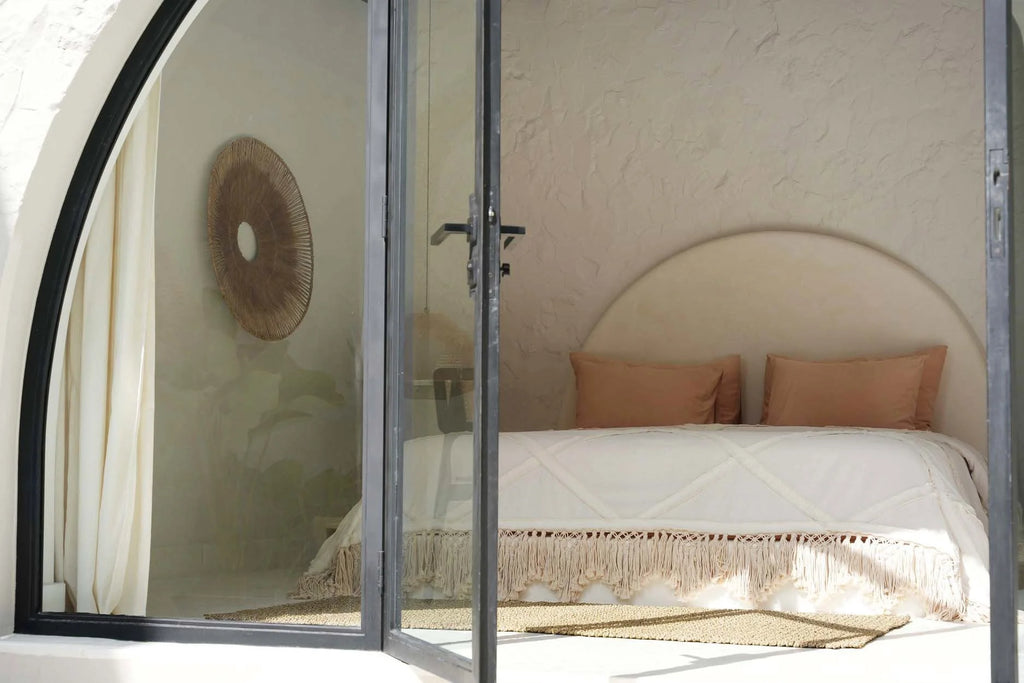 Image d’une chambre chaleureuse avec une literie en coton écru à franges et pompons