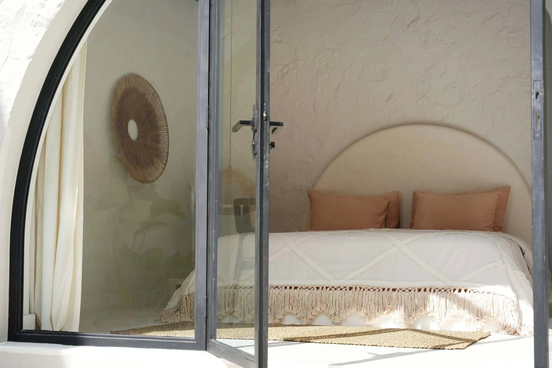 Image d’une chambre chaleureuse avec une literie en coton écru à franges et pompons