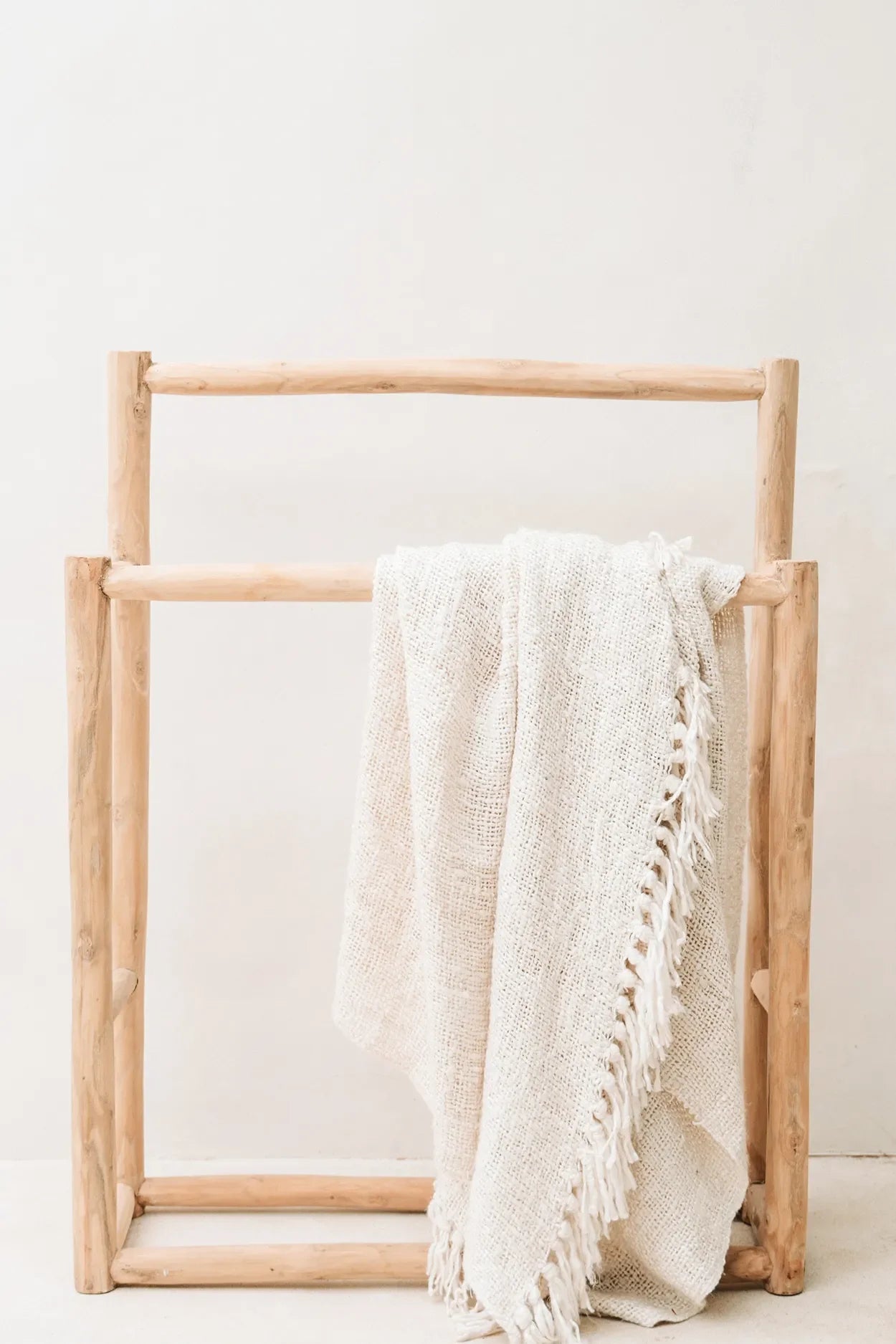 Towel rack en bois avec couverture en coton gaufré crème et franges décoratives