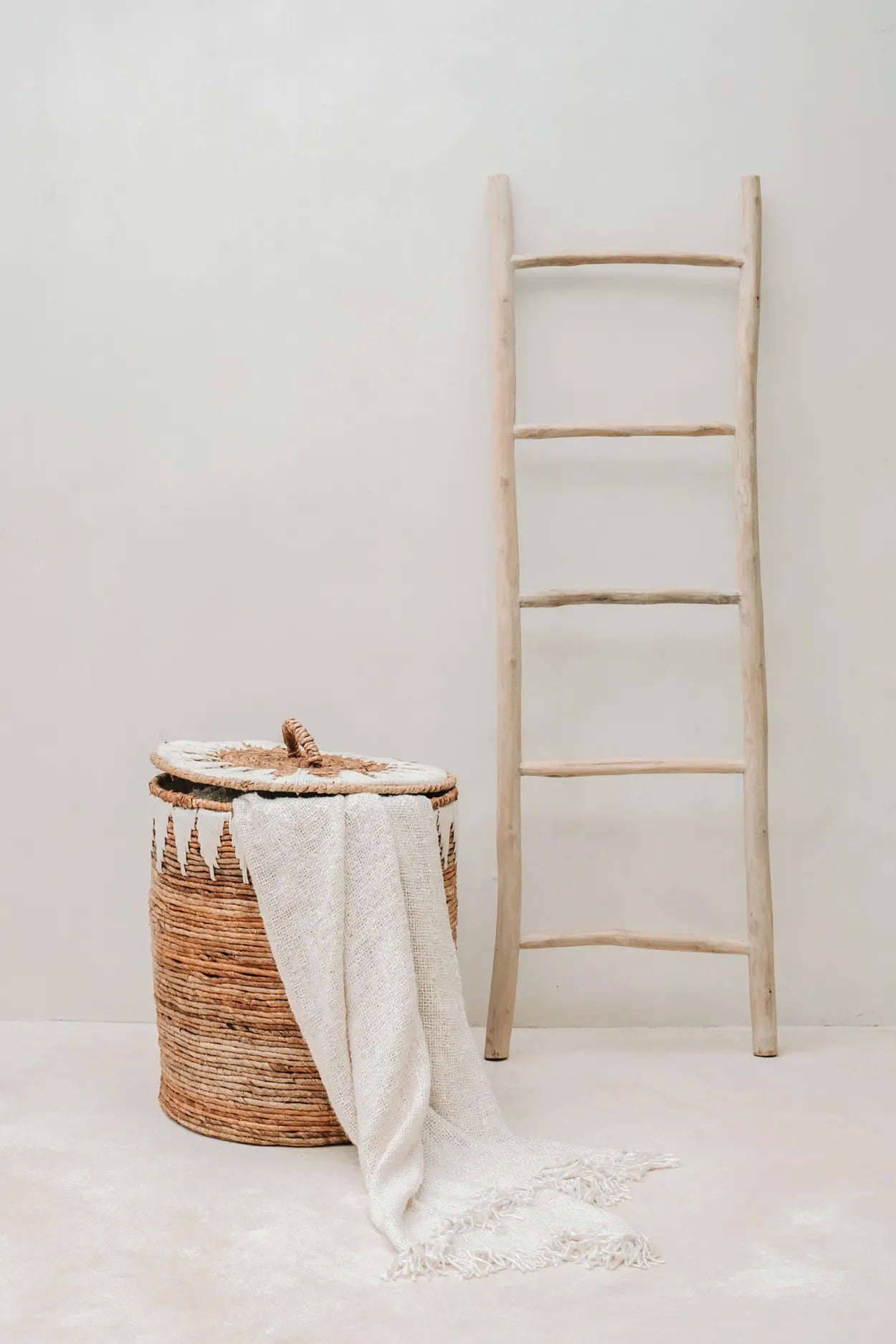 Panier en osier avec drapé blanc et échelle en bois pour décoration élégante