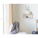 Fauteuil blanc avec plaid en coton recyclé à motifs losanges beige et noir avec franges