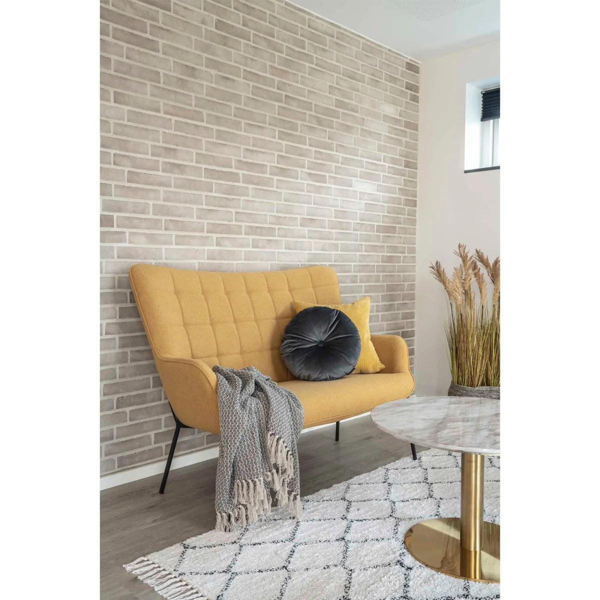 Canapé jaune à touffes, pieds métal noir, couverture grise, plaid coton gris-beige frangé