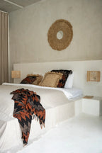 Plaid en coton tissé noir et orange à motif géométrique avec franges dans une chambre bohème avec accents texturés