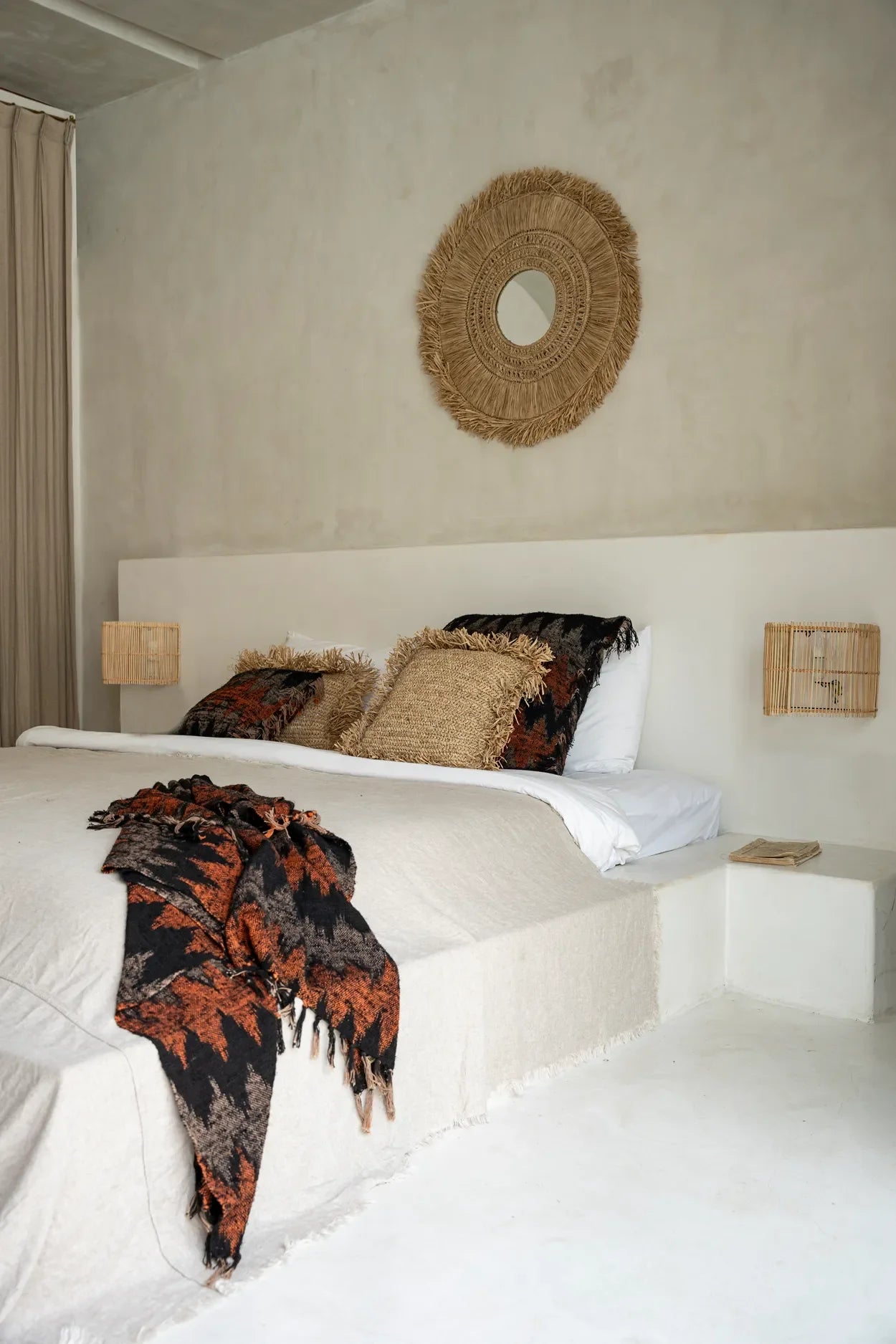 Plaid en coton tissé noir et orange à motif géométrique avec franges dans une chambre bohème avec accents texturés