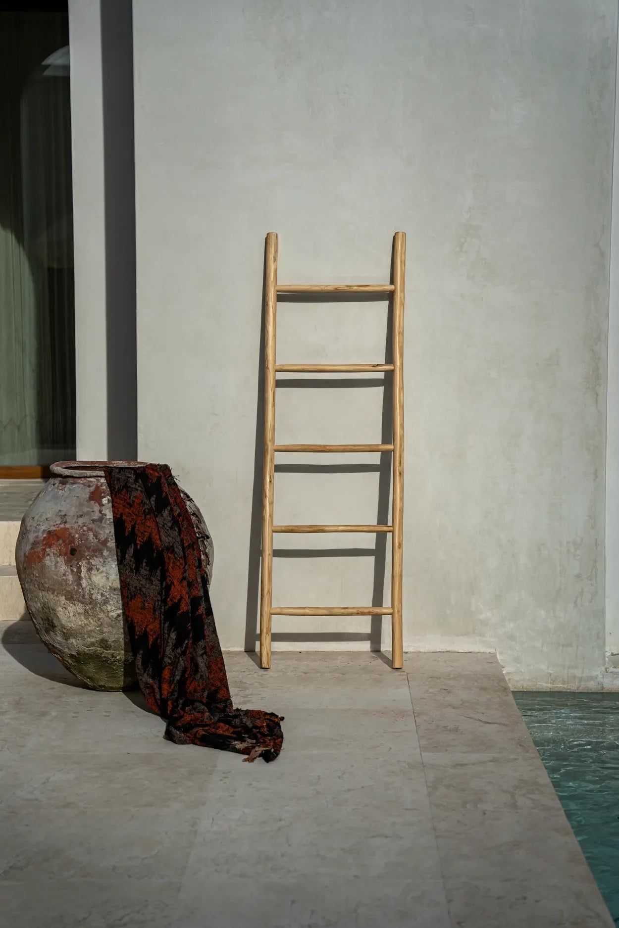 Échelle en bois avec cinq échelons devant le plaid en coton tissé noir et orange à motif géométrique