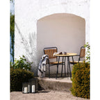 Table ronde en bois avec pieds métal noir et chaises assorties contre mur stuc blanc